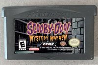 Front view of Game Boy Advance cartridge showing Scooby-Doo Mystery Mayhem label with Nintendo and THQ branding and ESRB rating E.