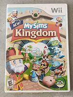 Front cover of MySims Kingdom Nintendo Wii video game case showing colorful cartoon characters and game title.
