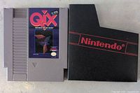 Front view of Qix NES video game cartridge with label and black Nintendo sleeve.