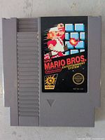 Front view of a Super Mario Bros Nintendo Entertainment System game cartridge showing label with pixelated Mario and title.