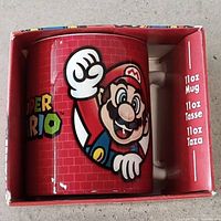 Front view of mug inside box showing Mario artwork and 11oz capacity