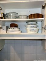 Upper cabinet showing stacked clear glass dishes, wooden bowls, and white fluted Corning dish