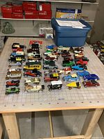 Wide view of 44 diecast vintage car and truck models arranged on a table with measurement grid.