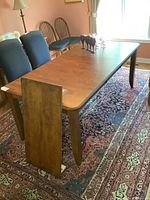 Full view of table with one leaf leaning against side, showing overall design and leg style