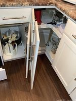 Open kitchen cupboards and drawer showing kitchen ware including utensils, bakeware, and cooking tools inside.
