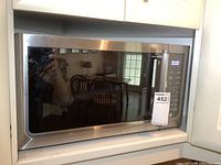 Microwave oven in kitchen built-in space showing full front including door and stainless steel frame.