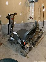 Three-quarter front view of scooter showing frame, seat, armrests, front wheels