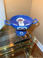 Blue vintage Moorcroft pedestal fruit bowl with handles and floral-fruit decoration shown on glass table. Visible crazing on surface.