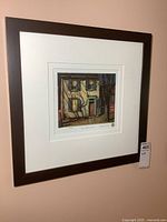 Full view of the framed print hung on a wall, showing the dark brown frame and white mat with the artwork centered.