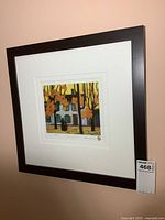 Framed signed and numbered print hanging on wall, showing full frame and matting.