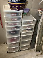 Two large white plastic organizer bins with seven and eight drawers stacked side by side. Each drawer is labeled with sewing and craft supply categories.