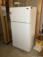 Full view of the white Kelvinator refrigerator with freezer showing front and side.