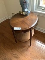 Straight-on top view showing oval wooden tabletop and decorative items (not included) on top.