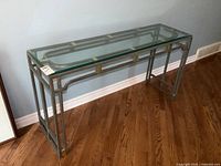 Side angle view of sofa table showing metal frame and glass top with beveled edges.