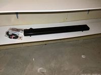 Black Panasonic SC-HTB70 sound bar on shelf with bundled cables and remote control.