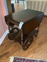 Full photo of the vintage wooden tea wagon with drop leaves in closed position on hardwood floor next to couch.