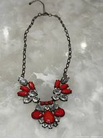 Full view of the necklace showing bronzed chain with attached red and clear rhinestones.
