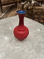 Oblique top view of red cinnabar vase showing neck and brass rim on a blue glazed interior.