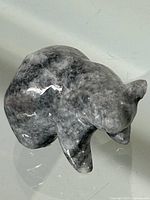 Top and side view of polished stone bear figurine showing grey and white marbled pattern and rounded bear shape