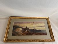 Full front view of framed watercolor painting showing two fishermen, boats and cart on a sandy beach within a gold decorative frame.