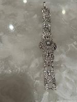 Full view of the 6.5 inch Art Deco silver-tone metal bracelet adorned with clear rhinestones, displayed on a shiny reflective surface.