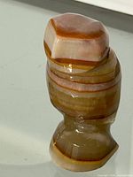 Front view of a polished carved onyx owl figurine showing distinct natural brown, cream and amber banding in the stone.