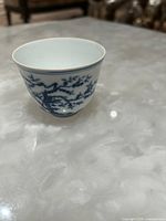 Angled view of cup showing blue tree and foliage design on porcelain surface