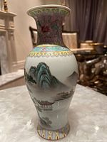 Porcelain vase showing detailed landscape painting with mountains, buildings, and water.
