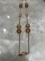 Close-up view of the necklace segment showing matte spherical beads with decorative gold toned bead caps and fine chain links.