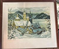 Front view of the framed art print showing the full winter scene of St. Jean, Quebec with snowy roofs, church towers, mountains, and lake.