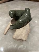 Front angle showing two carved stone seals on an antler base with detailed flippers and eyes.