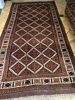 Full view of rectangular Iranian wool rug with geometric diamond lattice pattern and intricate border in shades of brown, red, and cream.