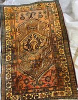 Full view of the rectangular beige and brown wool rug featuring two large hexagon medallions and floral geometric border designs.