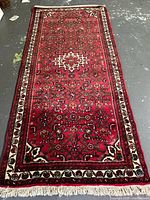 Full view of red wool rug showing overall pattern and fringe