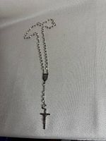 Full view of the metal ball chain rosary with crucifix displayed on a white surface.