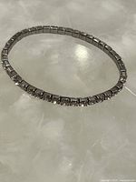 Full view of the silver-toned rhinestone bracelet lying flat to show entire shape and design.