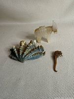 Lot overview showing the three items: metal shell and seahorse figurines, and carved crystal animal figurine.
