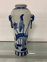 Front view of blue and white porcelain vase depicting lotus flowers and elephant head handle on one side