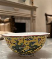 Side view of vintage Chinese yellow ground bowl decorated with multi-colored dragons and clouds.