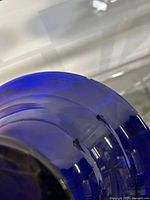 Close-up photo showing small chip on the rim of the cobalt blue glass bowl.
