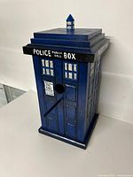 Front view of blue TARDIS birdhouse showing entry hole, perch, signage