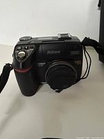 Front view of Nikon Coolpix 8400 camera with lens cap and strap