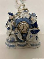 Front view of porcelain lamp base showing figures and clock