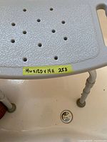 top view of perforated plastic shower seat with measurement label