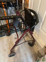 Side view of burgundy rollator showing frame, wheels, and hand brakes