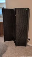 Room divider partially unfolded showing three wicker panels