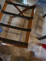 Top view of wooden luggage rack showing four black straps and brown frame