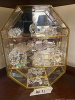 Full view of crystal figurines inside brass-framed glass display case
