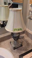 Full view of ornate cream table lamp with shade on countertop