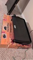 Electric griddle resting on original Presto box, power cord visible